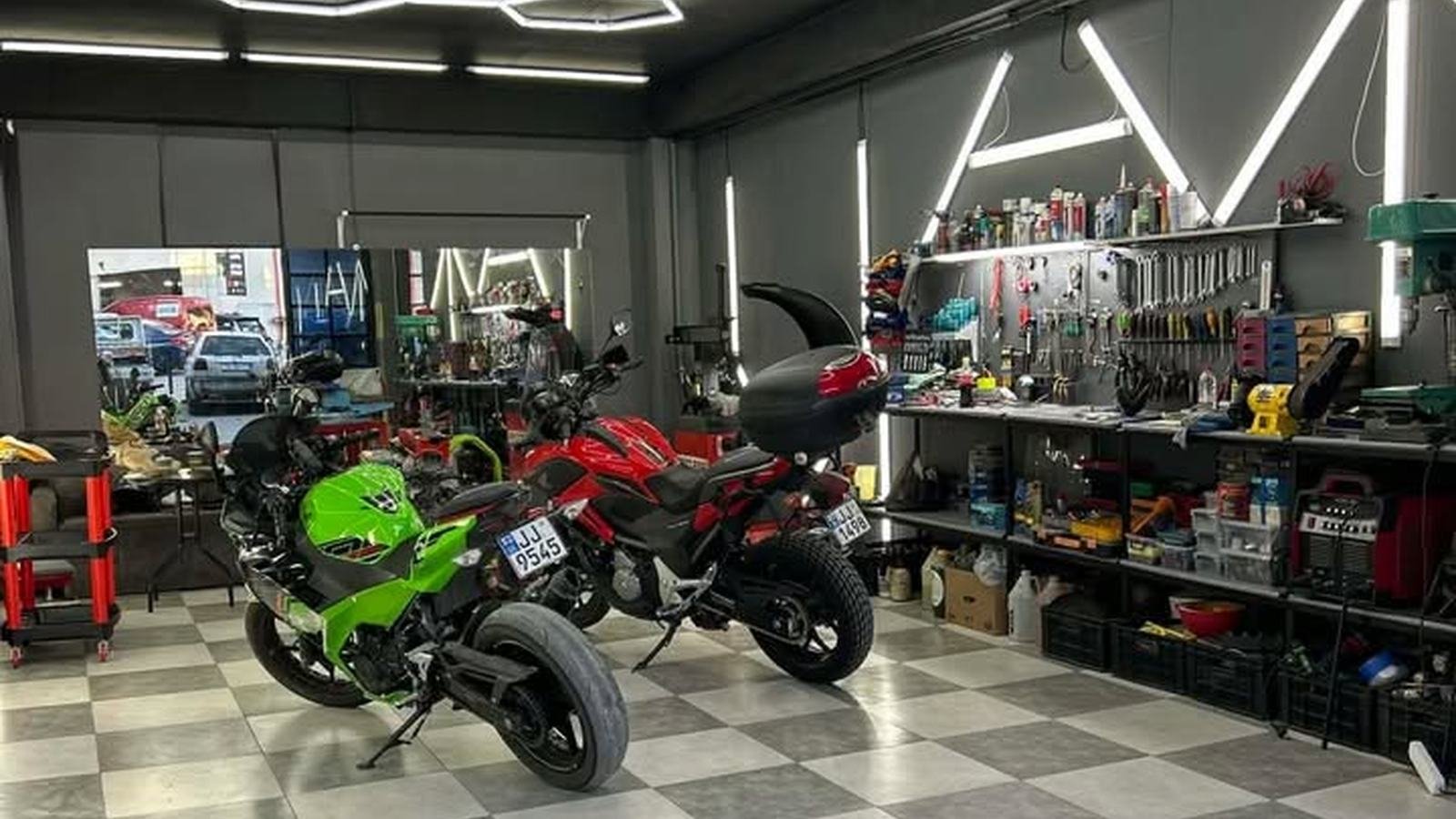 Motorcycle workshop floor with two bikes and a tool bench