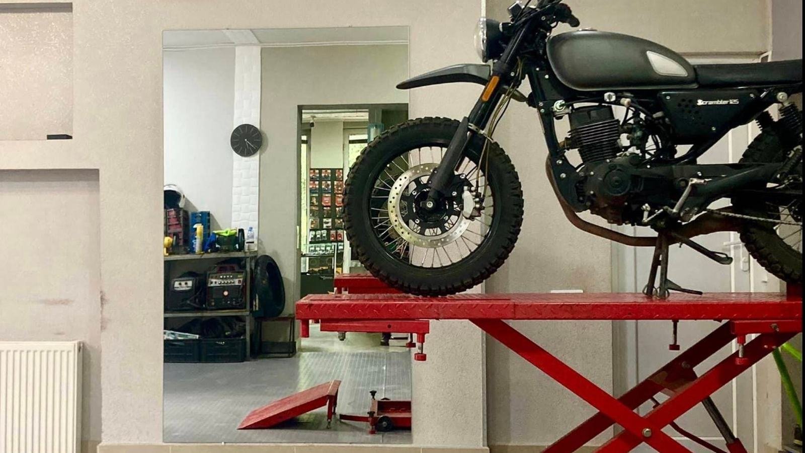 Motorcycle raised on a red workshop lift for servicing